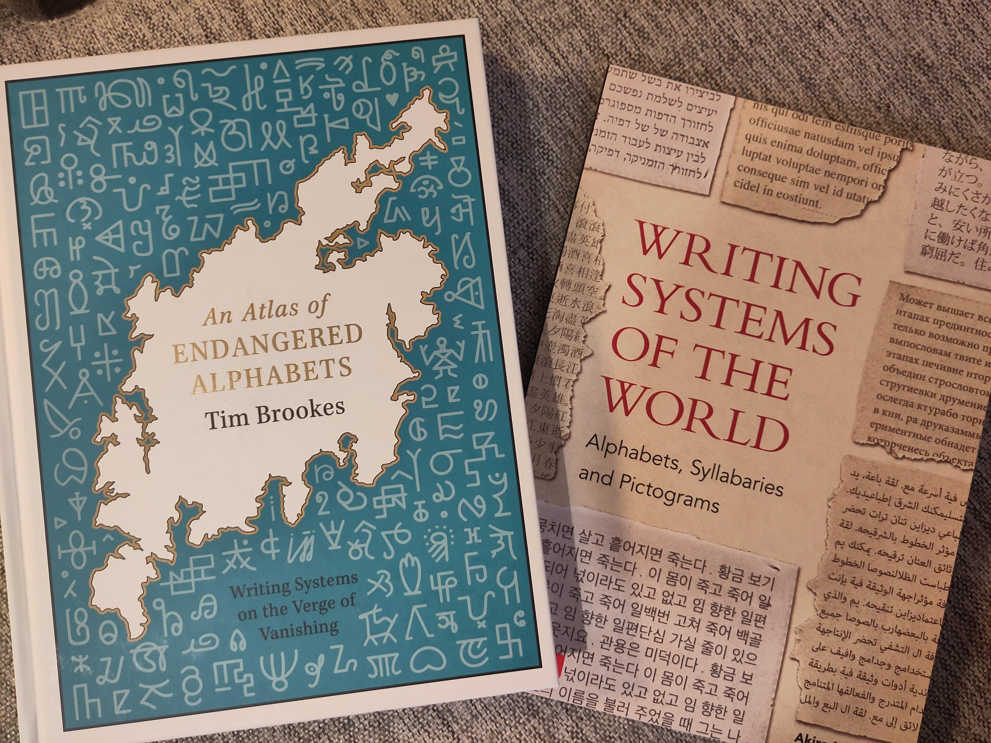 Photo of two books: Endangered alphabets, and Writing systems of the world