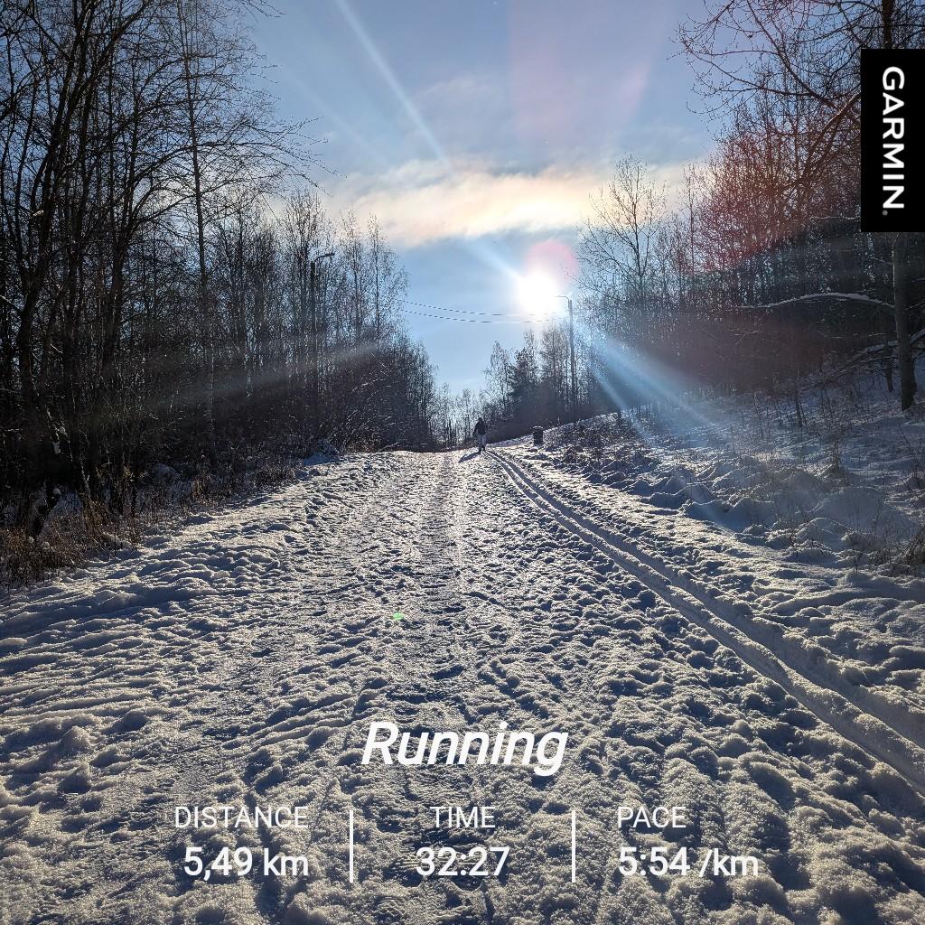 Luminen ulkoilureitti, jonka reunassa kulkee hiihtolatu. Taivas on sininen ja aurinko paistaa kirkkaasti. Juoksutilastot: matka 5,49 km, kesto 32:27 ja keskitahti 5:54 min/km.