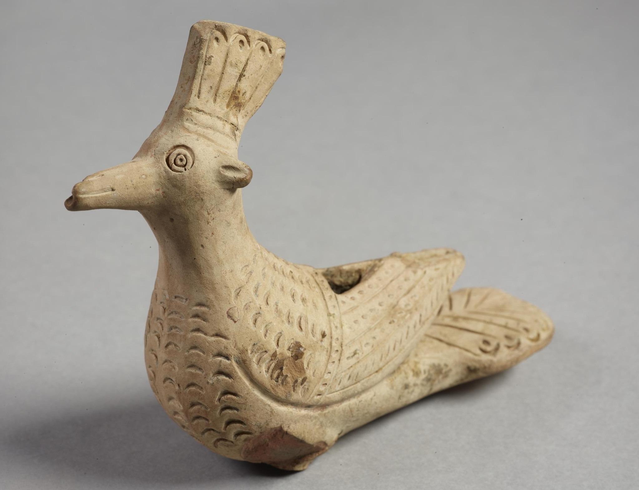 Savesta muovailtu linnun muotoinen puhallinsoitin eli kukkopilli. Linnulla on harja päässään, kuin harjalinnulla (Upupa epops). Harja on hiukan supussa. Linnulla näyttää olevan korvat. Sen pintaan on piirretty sulkien kuvioita. Se makaa siivet selkää myöten, ja sillä on ehkä ollut jalat, jotka ovat katkenneet. Linnun nokassa ja selässä on reiät, joten se on ehkä toiminut soittimena.