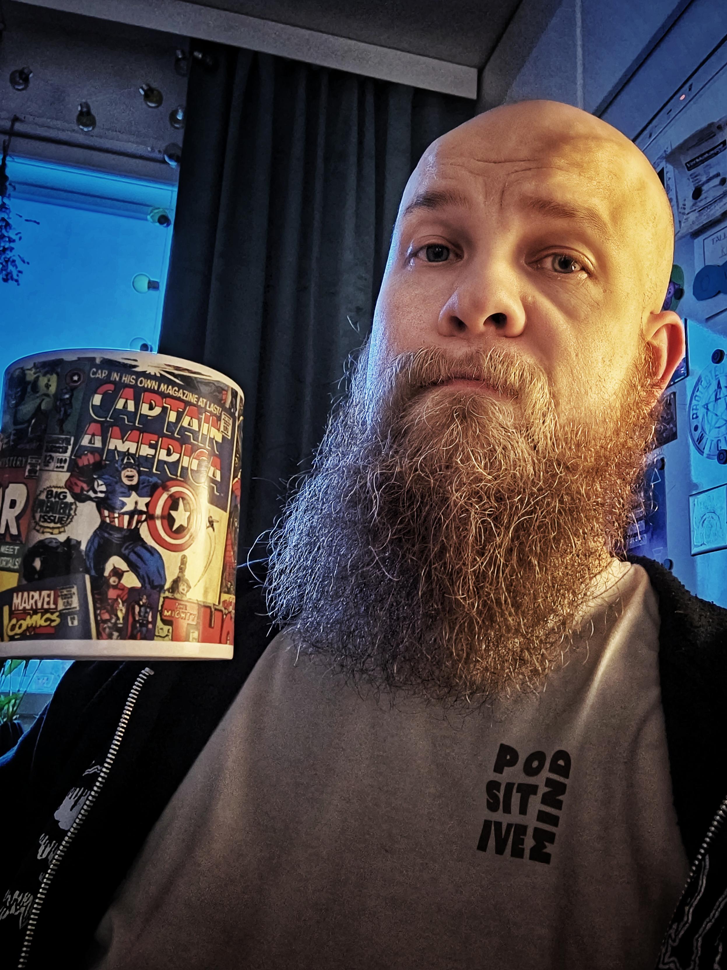 Selfie, jossa minä Marvel-aiheinen kahvikuppi kädessä ja parta ojossa.