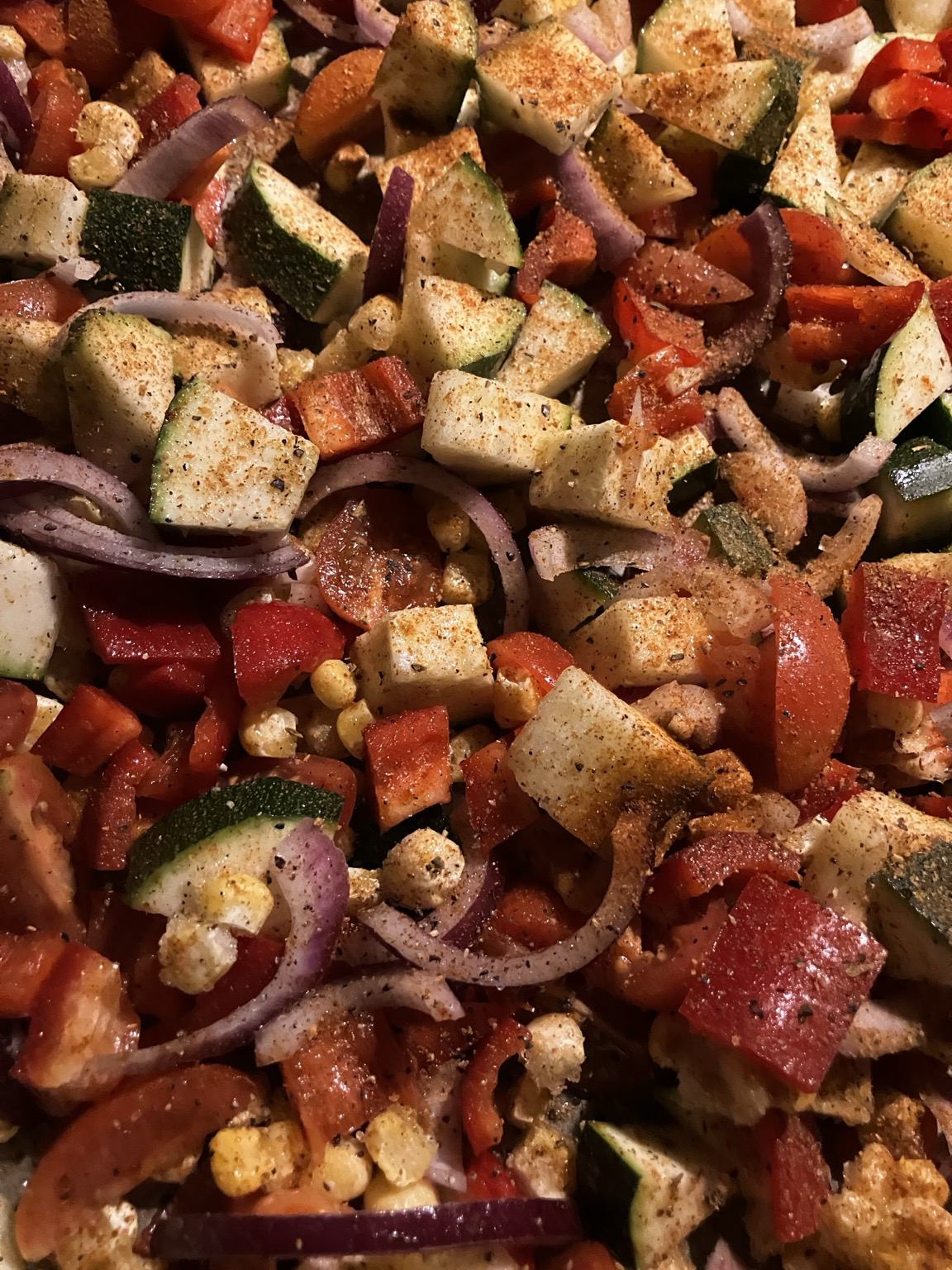 Uunipellillinen pilkottua kesäkurpitsaa, punasipulia, punaista paprikaa, kirsikkatomaatteja ja maissia. Päällä mausteita.