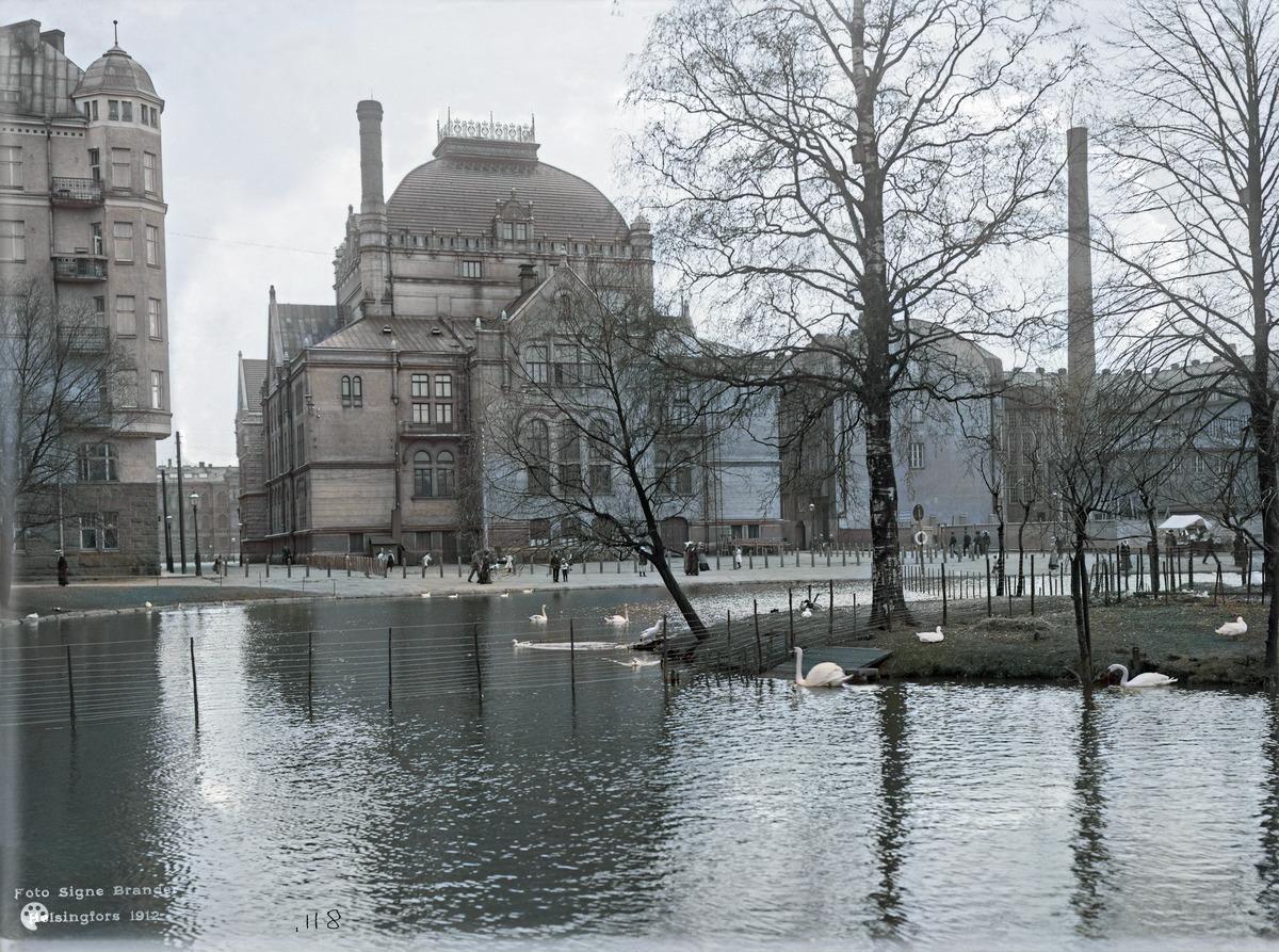 Kaisaniemen lammikko. (1912, Helsingin kaupunginmuseo)

Alkuperäisen valokuvan on ottanut Signe Brander. Tämä kuva on keinotekoisesti väritetty DeOldify-algoritmilla.