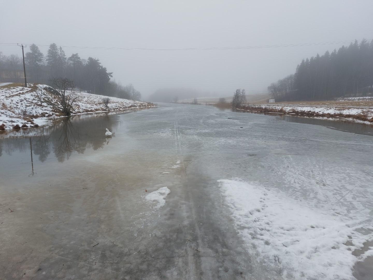 Näkymä Kuralansillalta Aurajokea alespäin. Jäällä vettä ja vielä sulamatonta hiihtolatua lukuisten jalan- ja polkupyöränkin jälkien ohessa. Sumu miltei kätkee Virnamäen, jossa äsken oltiin. Joen jäälle näkyy joku tehneen ja kiinnittäneen lumikasan, joka kauempaa näytti melkein joutsenelta.