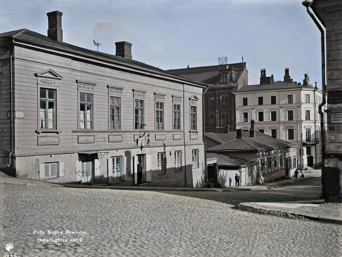 Konstantininkatu 7, 5 (= Meritullinkatu ). (1909, Helsingin kaupunginmuseo)

Alkuperäisen valokuvan on ottanut Signe Brander. Tämä kuva on keinotekoisesti väritetty DeOldify-algoritmilla.