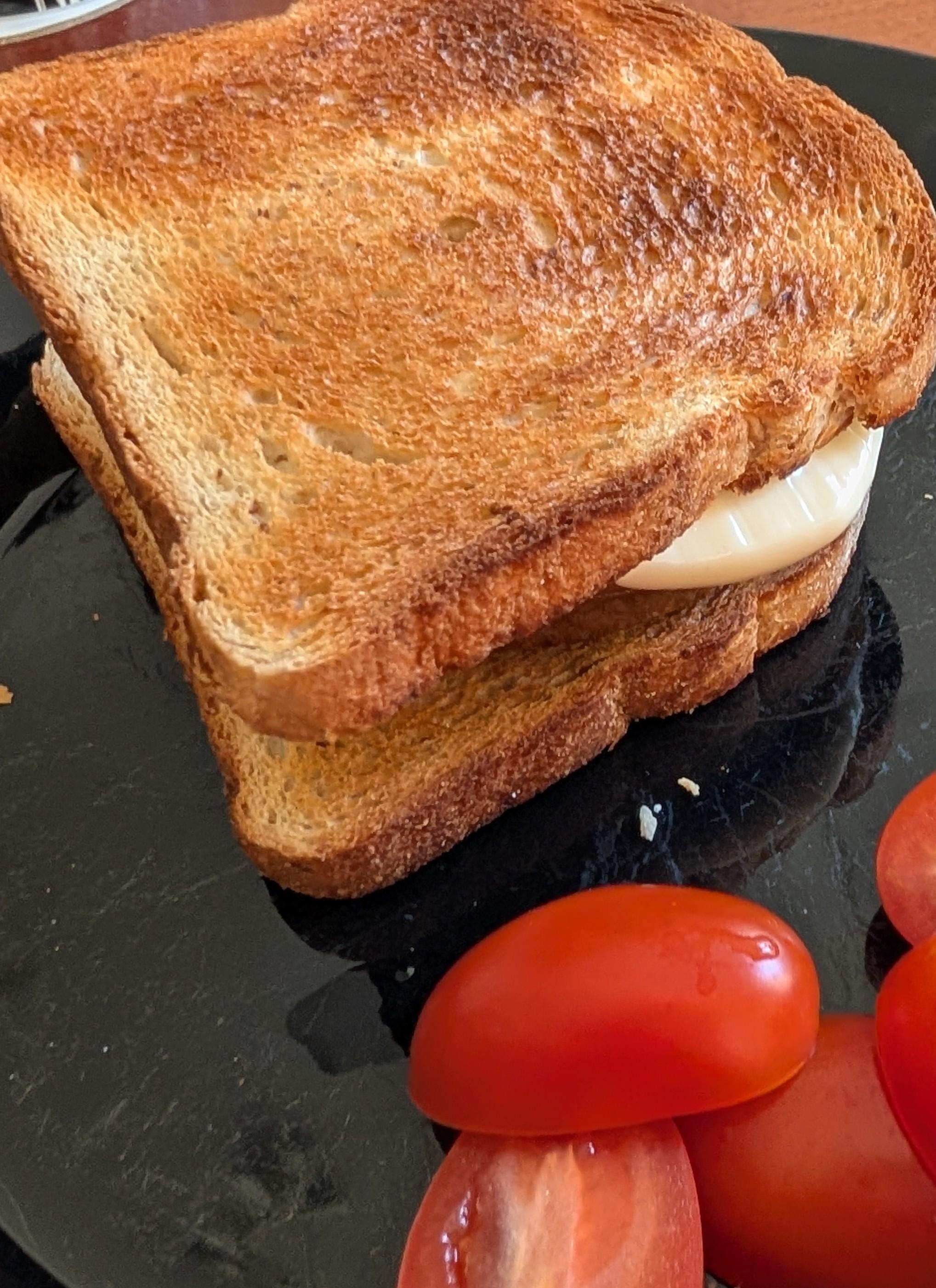 Patty with smoked cheese between toast slices and some tomatoes