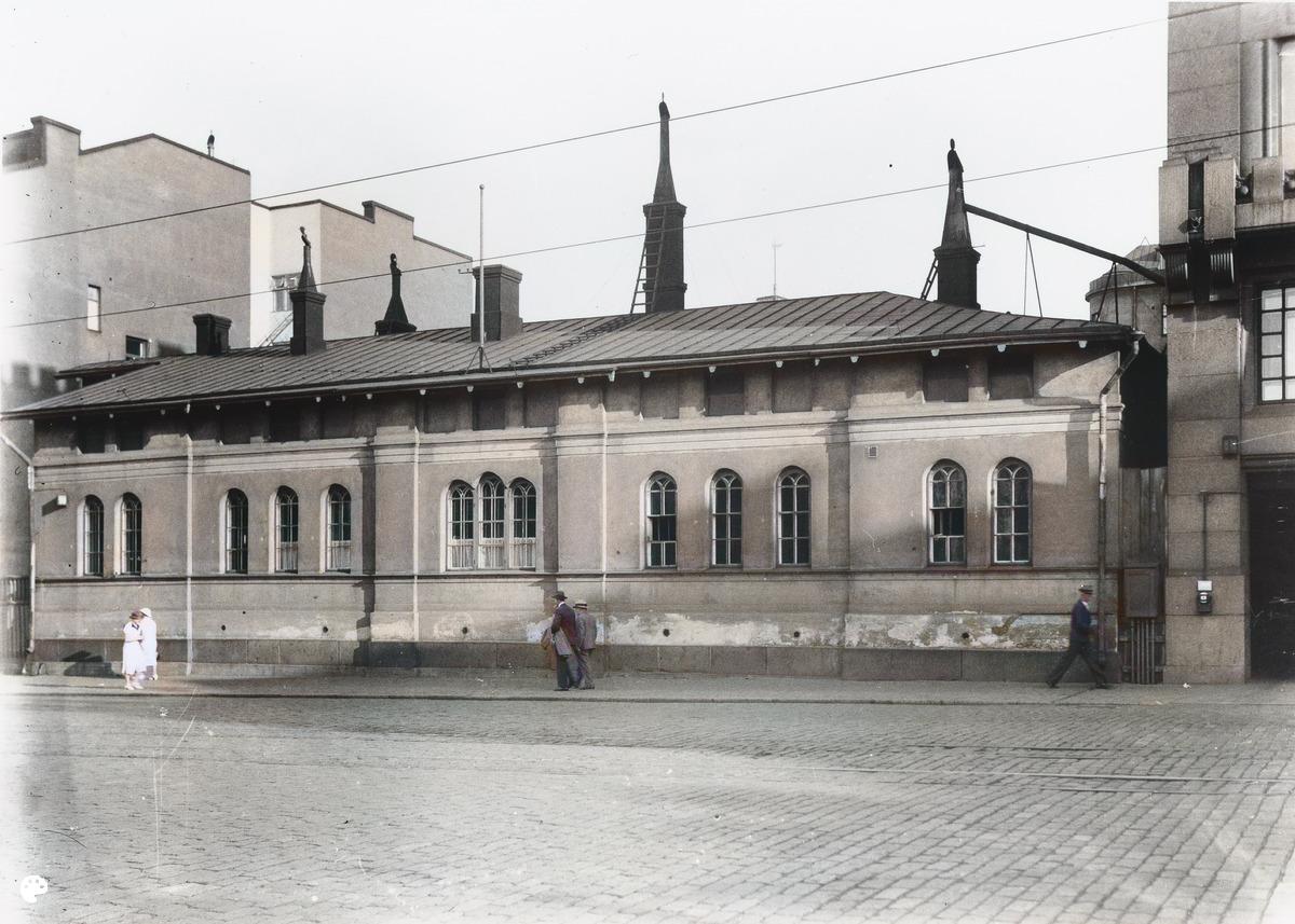 Kaivokatu 10. (1930, Helsingin kaupunginmuseo)

Alkuperäisen valokuvan on ottanut Signe Brander. Tämä kuva on keinotekoisesti väritetty DeOldify-algoritmilla.