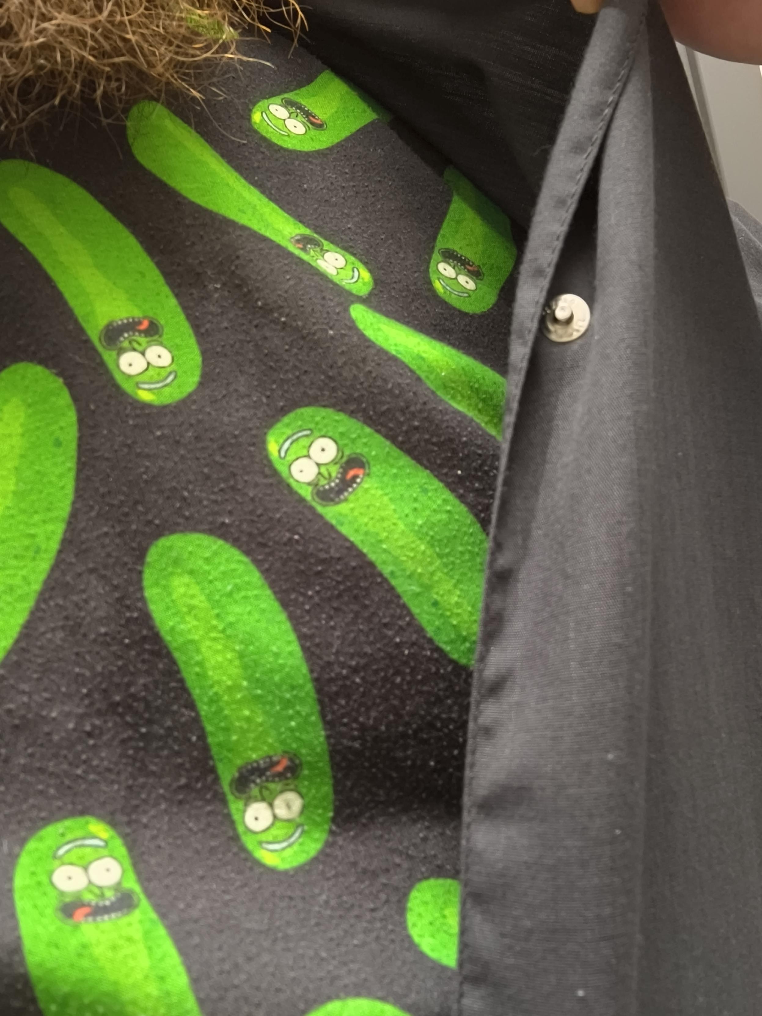 Kuvassa työtakin alla näkyvä t-paita, jossa Rick & Morty -piirrossarjasta tuttu Pickle Rick.
