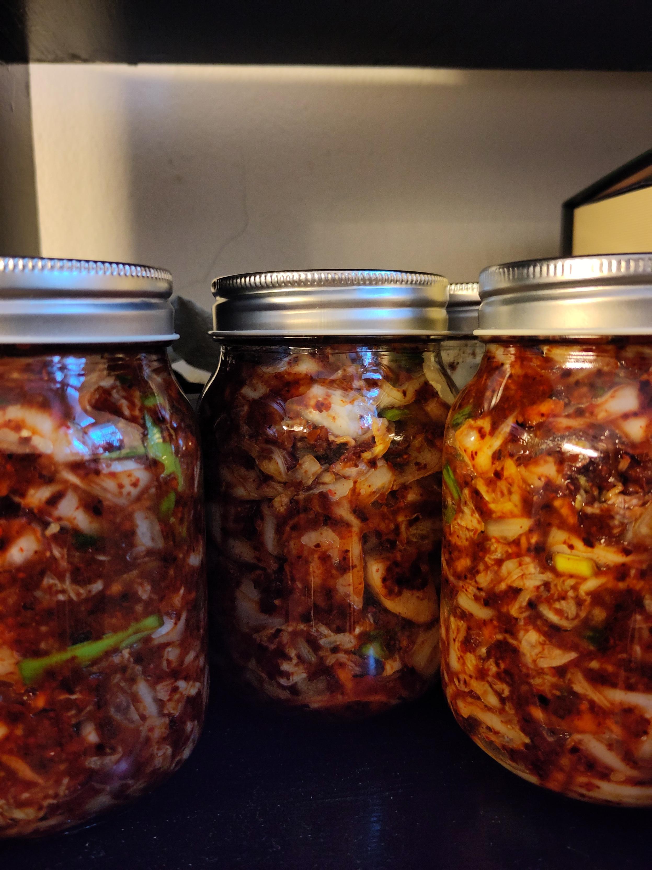 Kolme lasipurkkia, joissa sisällä kimchiä.