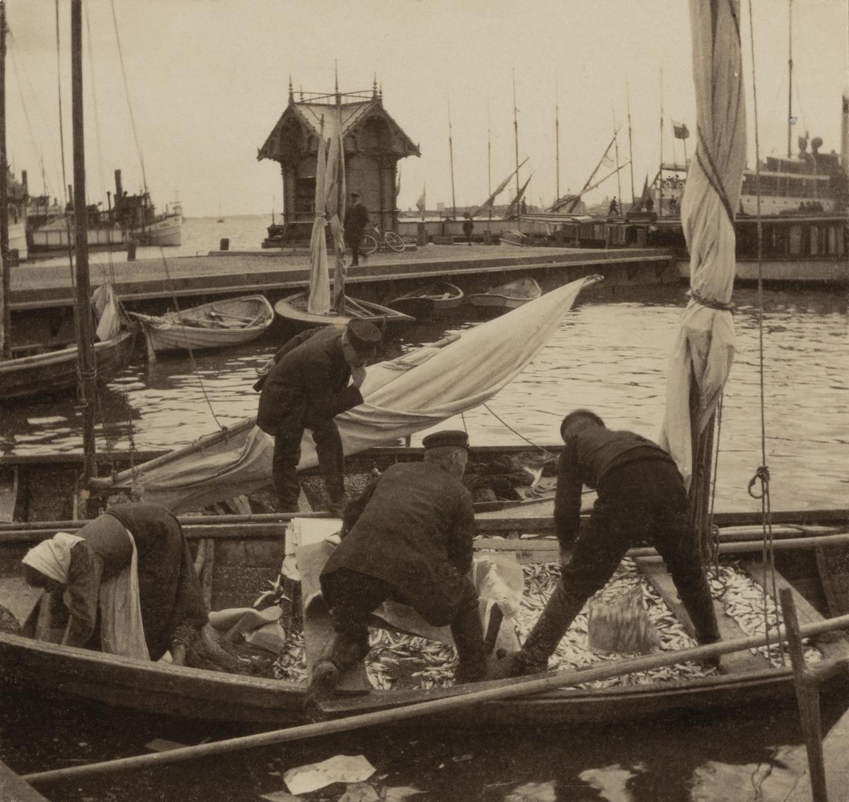 Kauppatori, kalastajia veneessään syys- eli silakkamarkkinoiden aikaan. (1912, Helsingin kaupunginmuseo)

Alkuperäinen mustavalkoinen valokuva, jonka on ottanut Ivan Timiriasew.