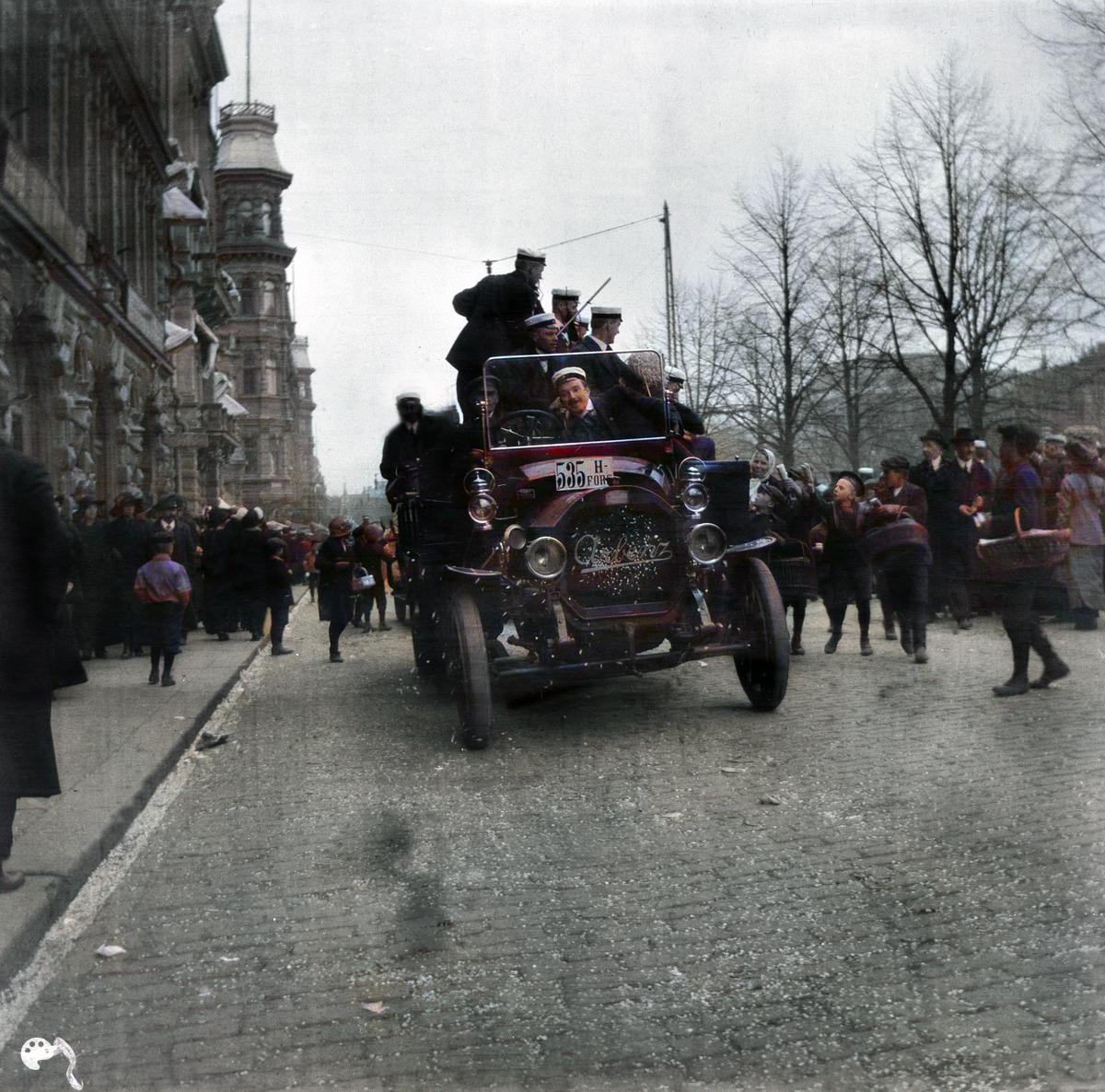 Vapunviettoa Pohjois Esplanaadikadulla. (1910, Helsingin kaupunginmuseo)

Alkuperäisen valokuvan on ottanut Ivan Timiriasew. Tämä kuva on keinotekoisesti väritetty DeOldify-algoritmilla.