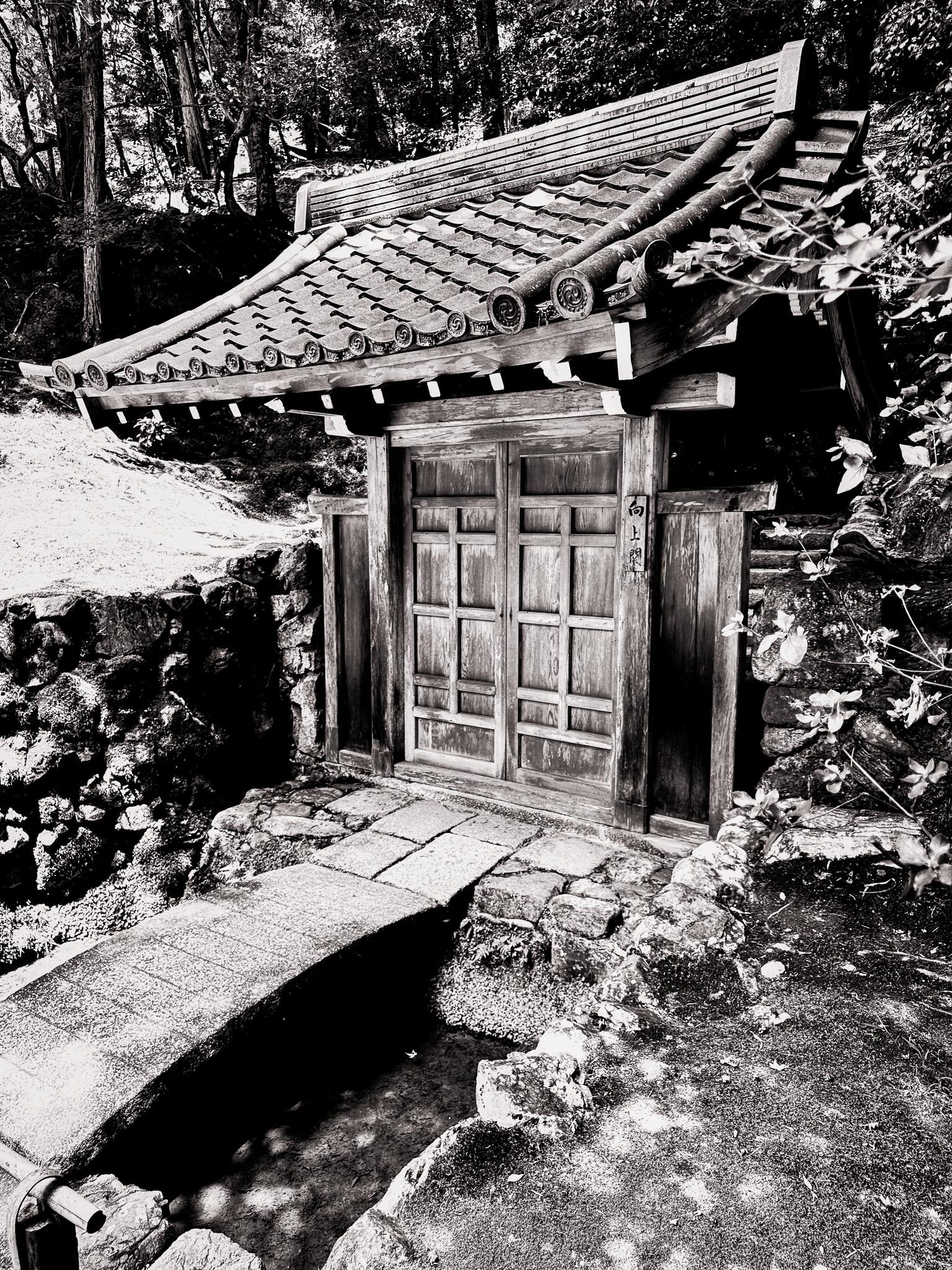 small work shack in japan built in the old style with tiled roof and bamboo gutters — in black and white