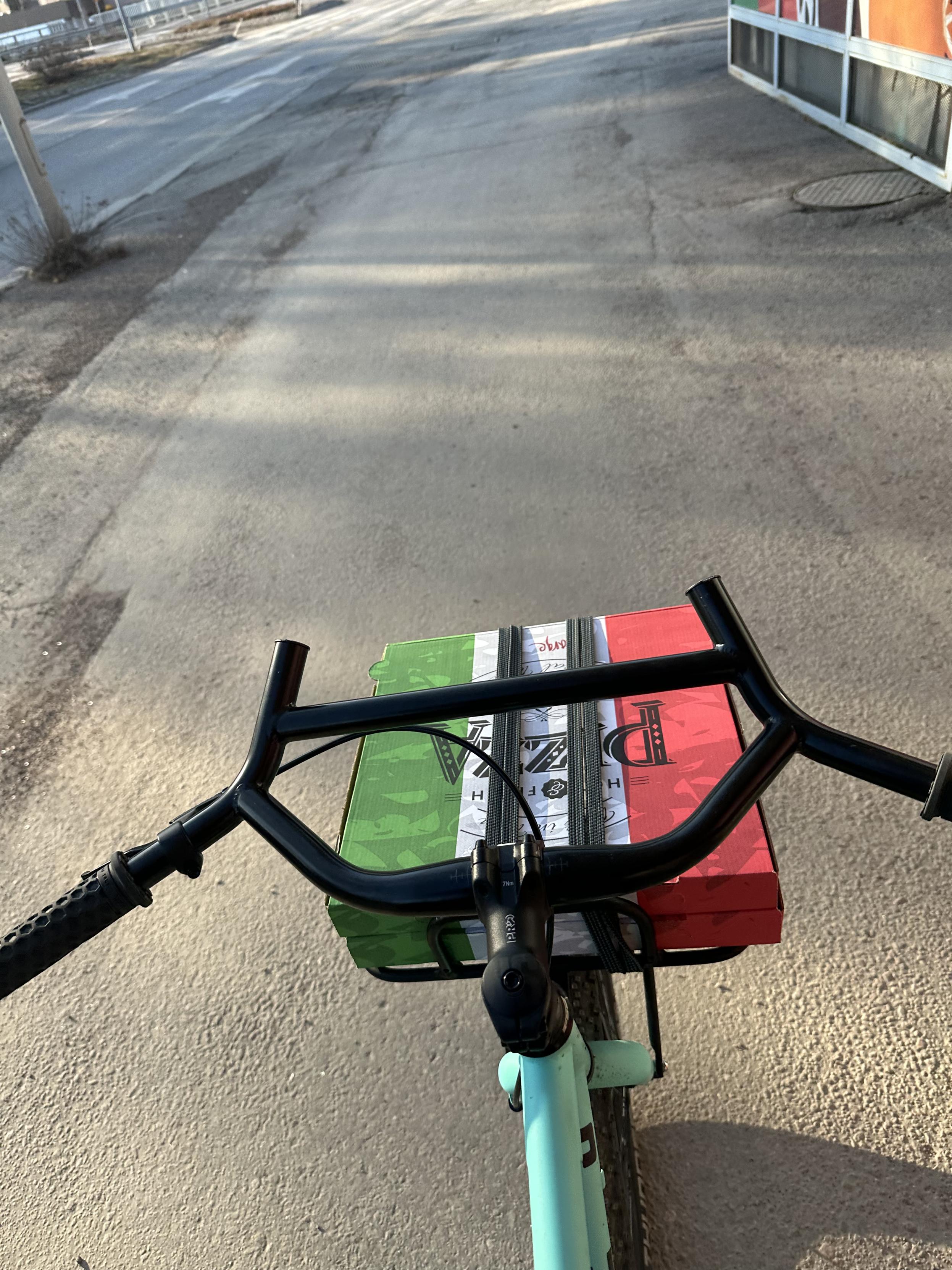 Sama pyörä kuvattuna kuskin paikalta, alt-barin takana näkyy pizzalaatikon kansi.