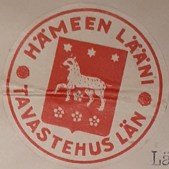 Hämeen läänin vaakuna 1920-luvun alusta ja sitä ympäröivä teksti: Hämeen lääni - Tavastehus län. Väri: Punainen. Vaakunassa on kolme kuusisakaraista tähteä, ilves ja neljä ruusua.