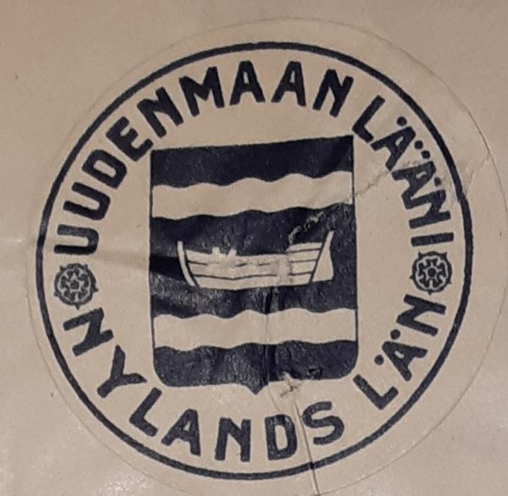 Uudenmaan läänin vaakuna 1920-luvun alusta ja sitä ympäröivä teksti: Uudenmaan lääni - Nylands län. Väri: Tummansininen. Vaakunassa on sinisessä kentässä kaksi vaakasuoraa aaltomaista nauhaa (heraldiikan kielellä: kaksi aaltokoroista hopeahirttä) ja niiden välissä peräsimellä varustettu vene.