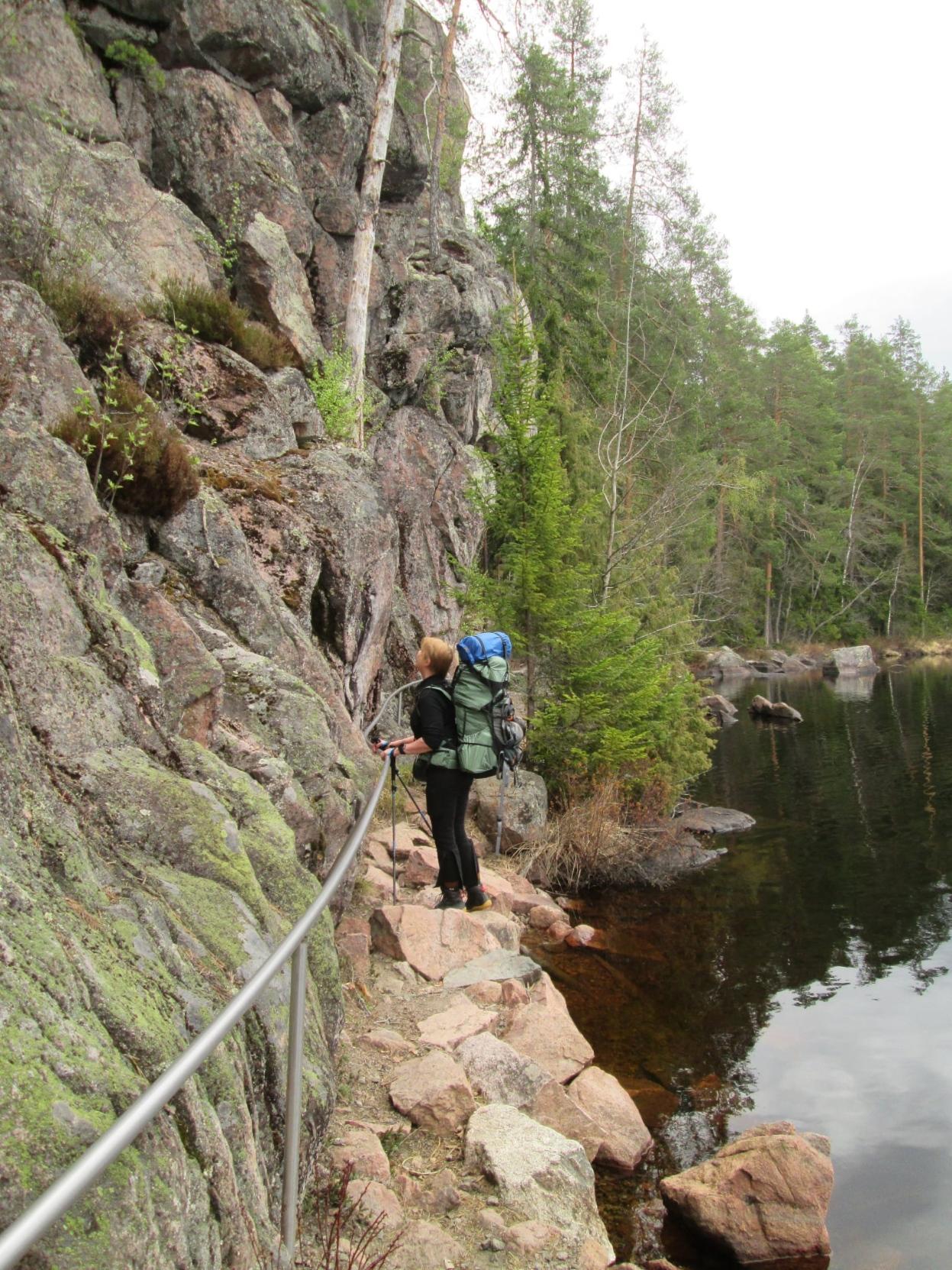 High cliffs on left and narrow path between cliff and lake.