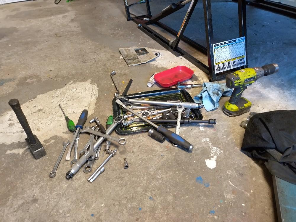 Kasa työkaluja autotallin lattialla - osa metallitarjottimen päällä, toinem mokoma vieressä