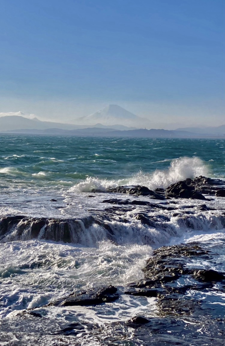View to Mt. Fuji from Enoshima, very blue ocean and waves crashing to rocks in the foreground